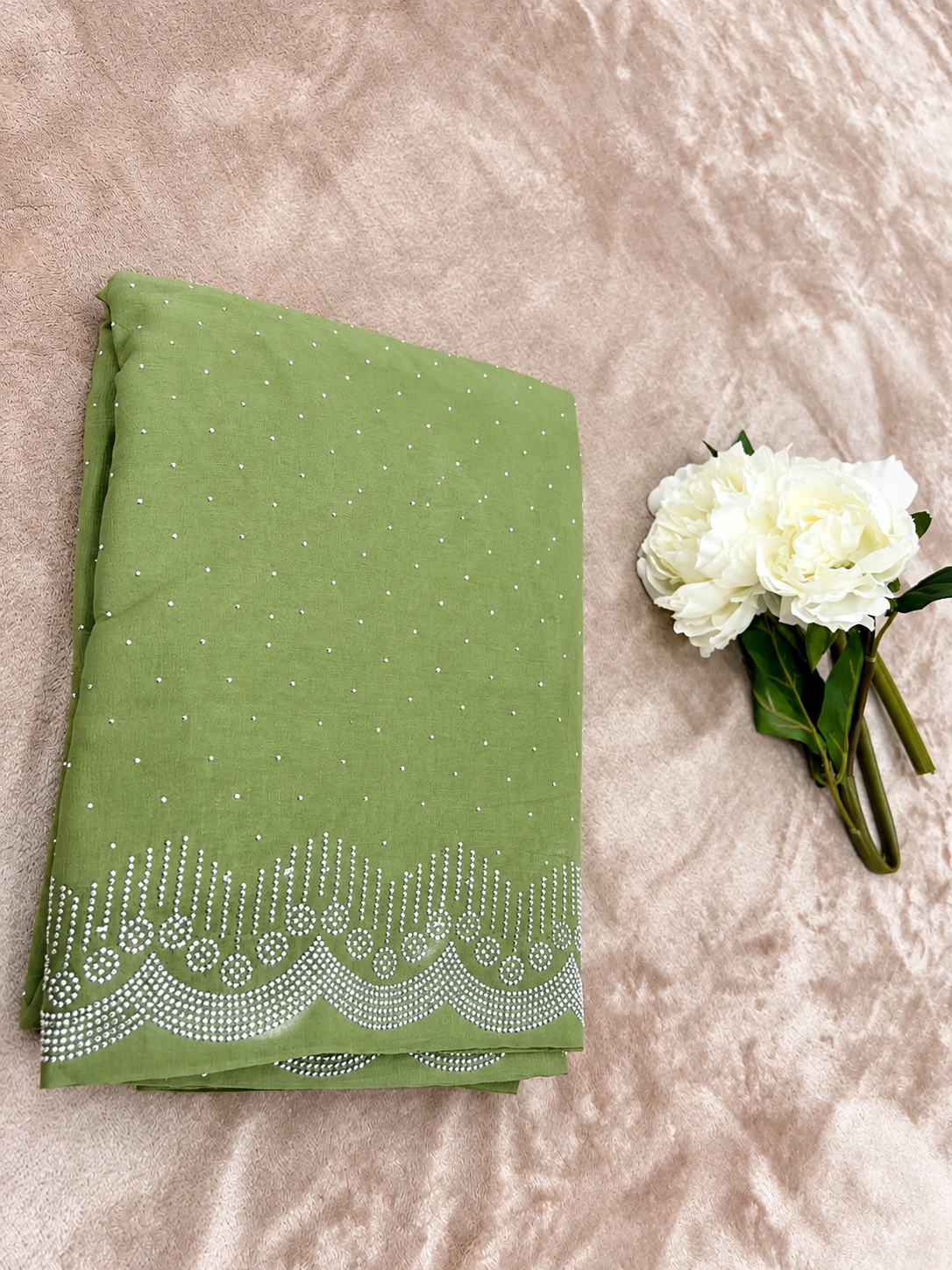 Sage green saree flat lay showing scalloped cutdana border detail