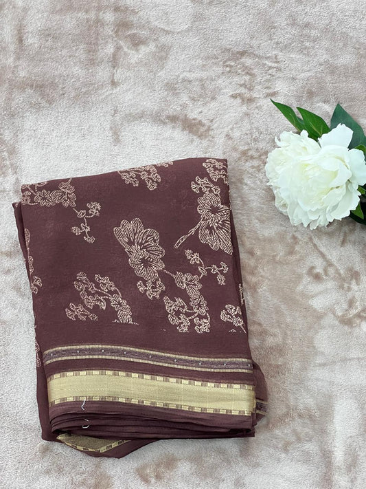 Chocolate brown saree folded flat lay with white peony showing gold zari border