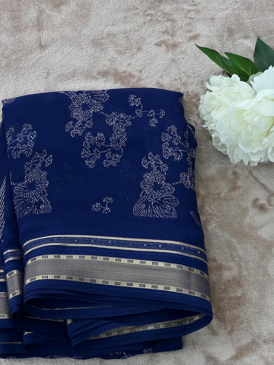 Royal blue saree folded flat lay with white peony