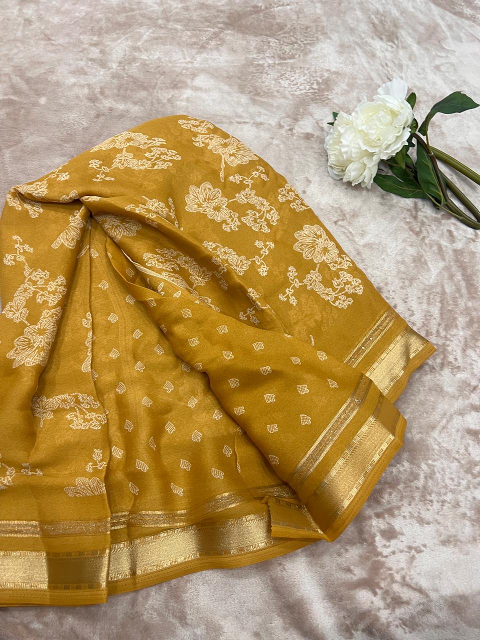 Golden mustard saree flat lay with white peony showing heart butti and zari border