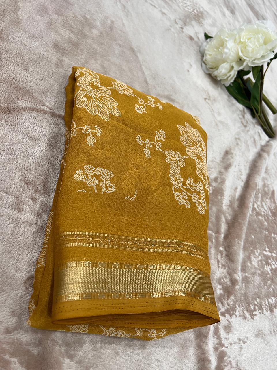 Golden mustard saree folded showing cutdana floral motifs and gold zari border close-up
