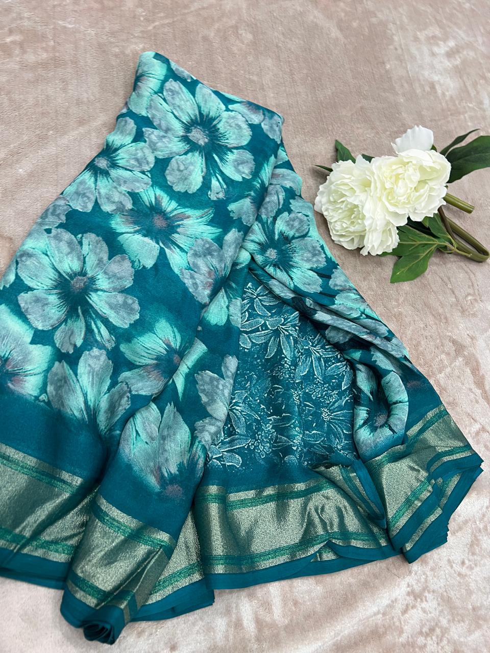 Rasmalai teal saree draped flat showing large hibiscus print and embroidered pallu with gold-green border