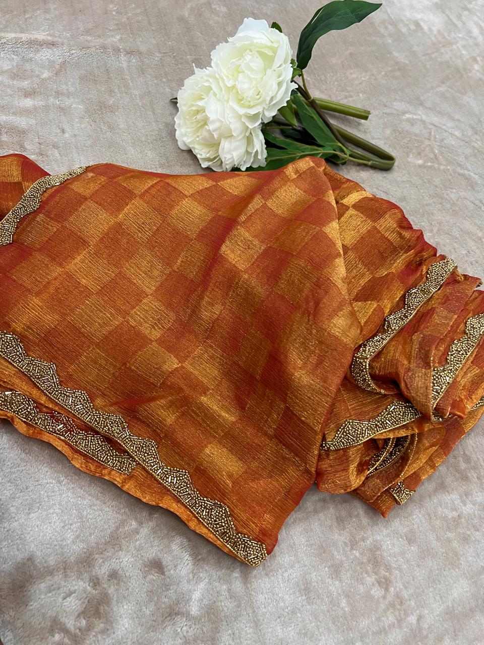Burnt orange zari check saree folded flat lay close-up showing gold cutdana scalloped border