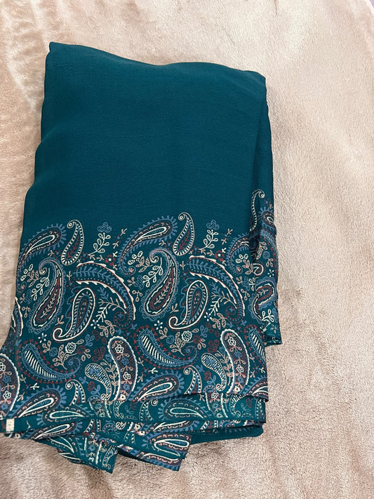 Teal green saree folded flat lay showing plain body transitioning into Kashmiri paisley print border